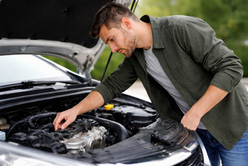 Mężczyzna sprawdzający elementy silnika samochodu osobowego przed zakupem, używając checklisty kontroli auta